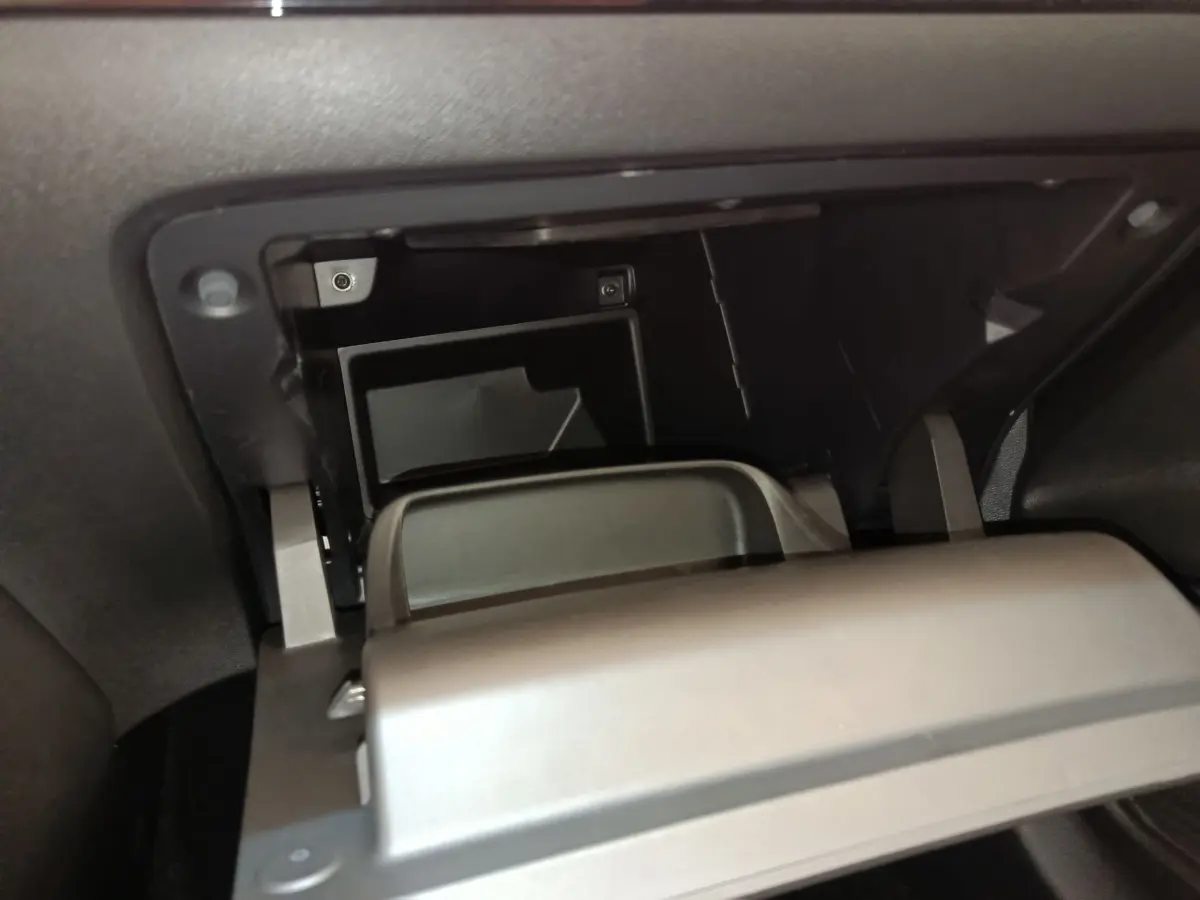 Gros plan intérieur sur la boîte à gants ouverte de la Peugeot 208 PureTech 75 S&S Style 2023, finition noire.