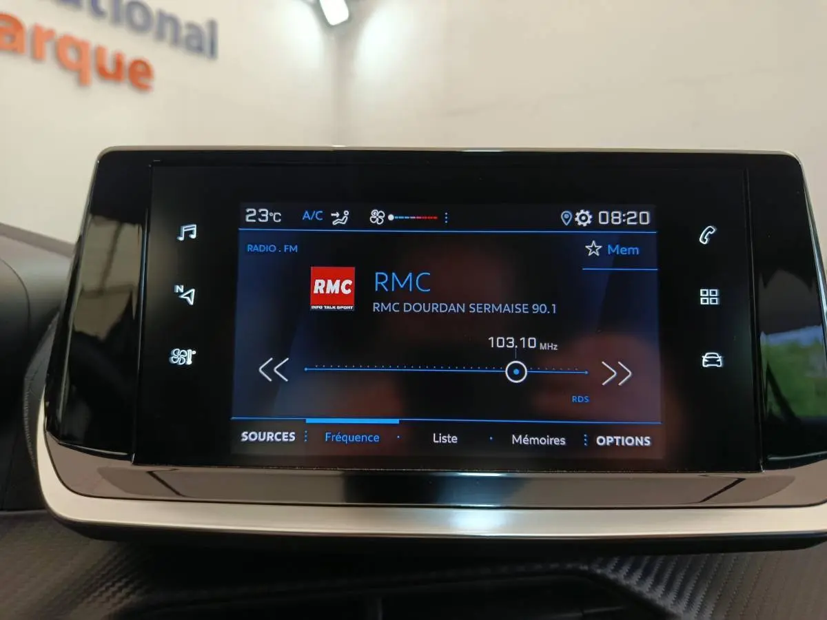 Écran tactile central de la Peugeot 208 blanche PureTech 75 S&S Style affichant la radio RMC à 103,10 MHz.