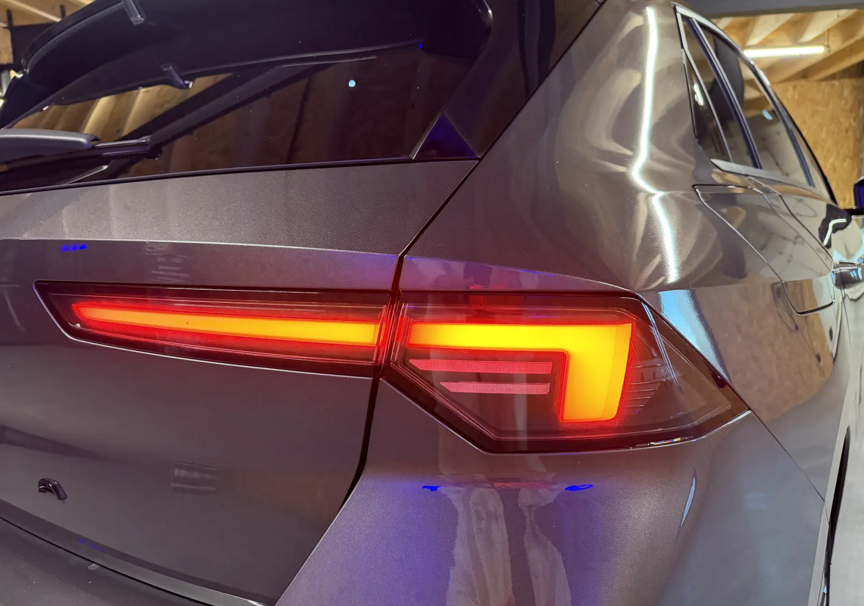 Feu arrière allumé en gros plan sur le côté droit d’une Opel Astra gris métallisé 2024 dans un garage.