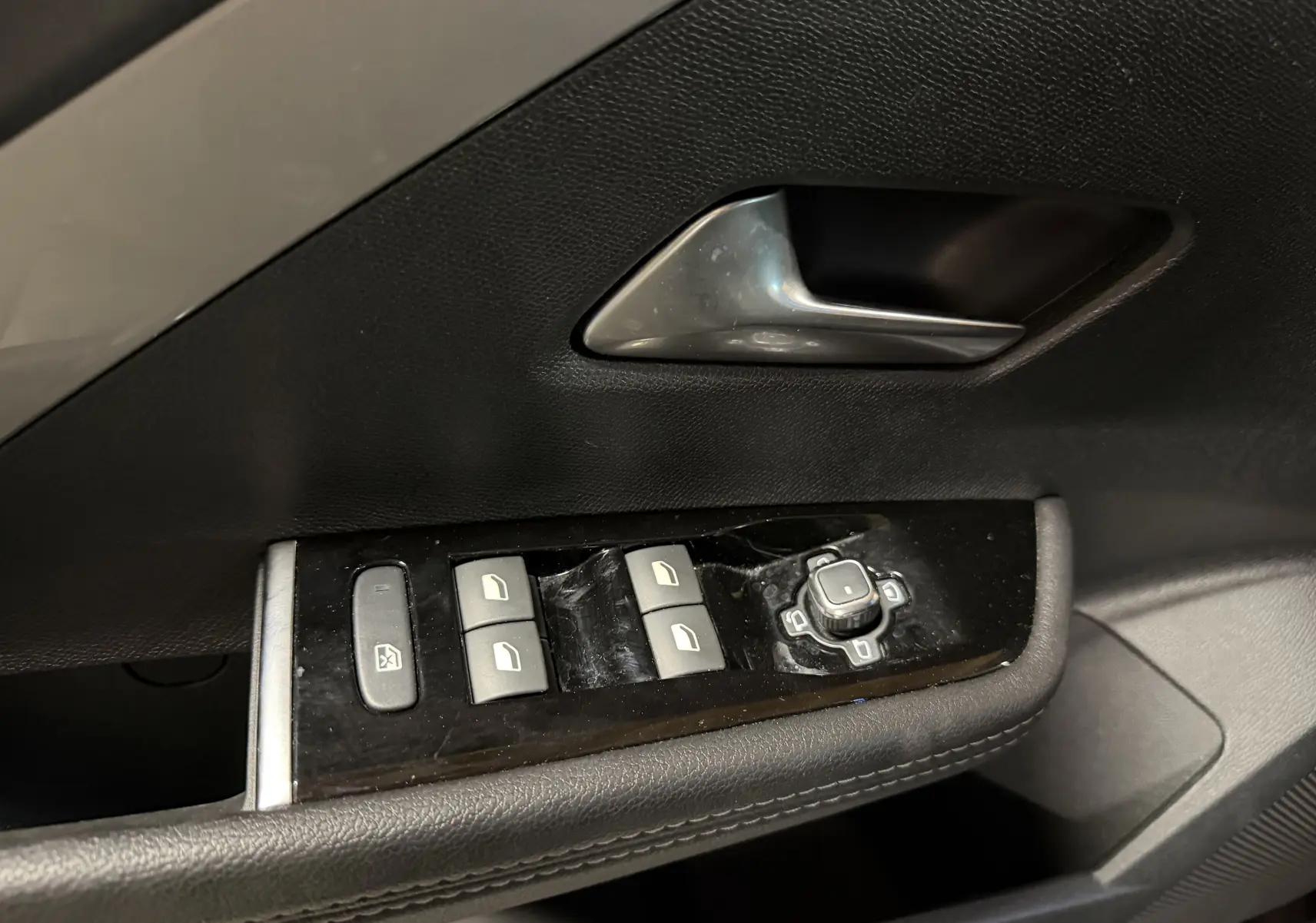 Gros plan sur la commande des vitres et rétroviseurs côté conducteur de l'Opel Astra gris 2024.