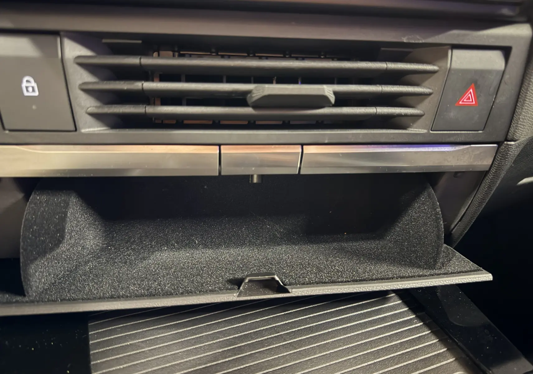 Gros plan sur la boîte à gants ouverte et la ventilation centrale du tableau de bord intérieur noir de l’Opel Astra 2024.
