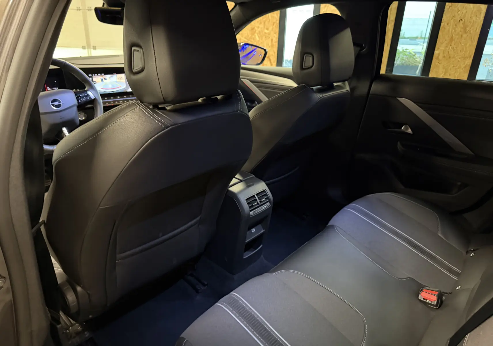 Vue arrière intérieure de l’Opel Astra 2024, sièges noirs en cuir et tissu avec console centrale et ventilation arrière.