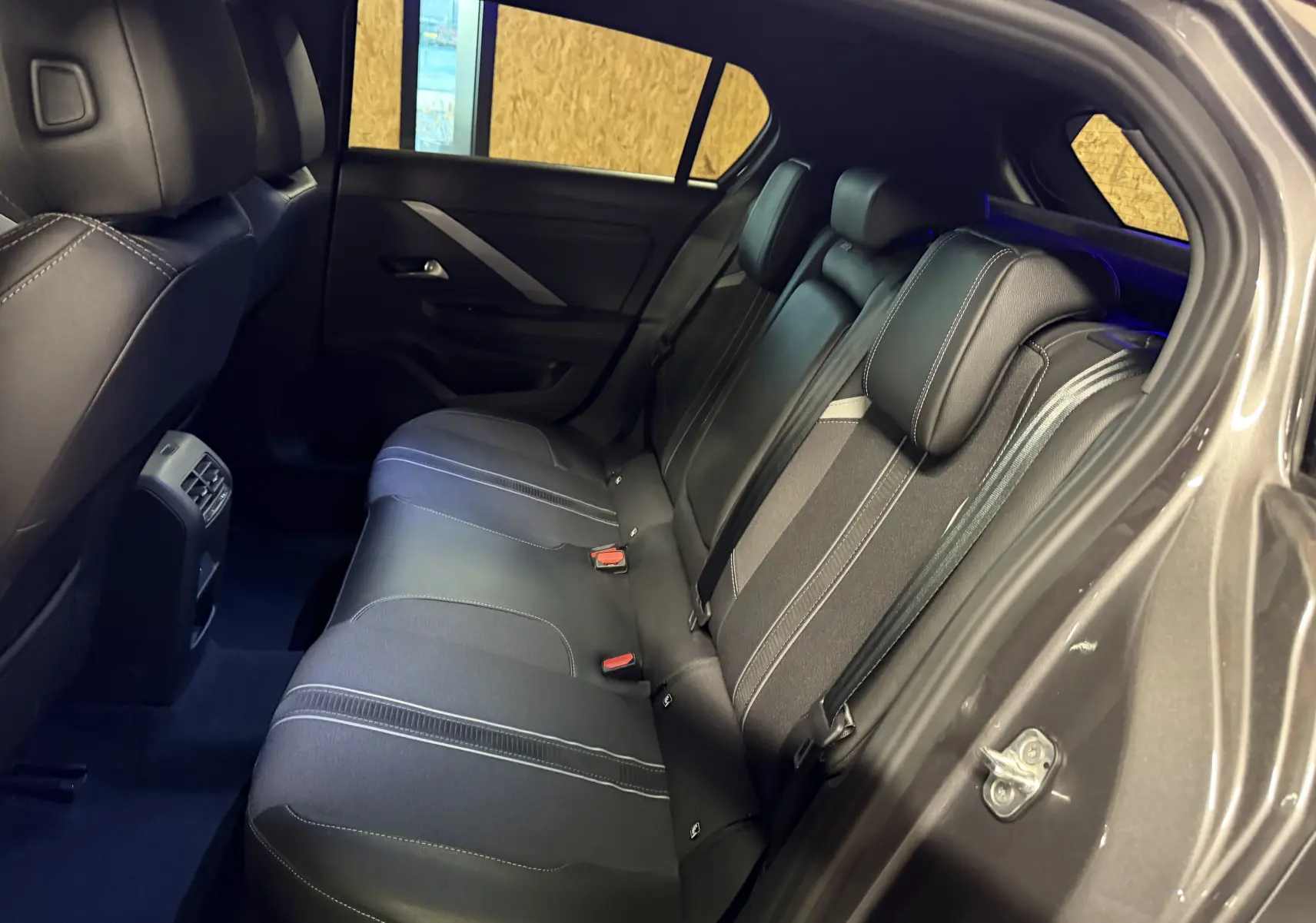 Vue intérieure côté droit sur la banquette arrière noire avec surpiqûres blanches de l’Opel Astra 2024 gris métallisé.