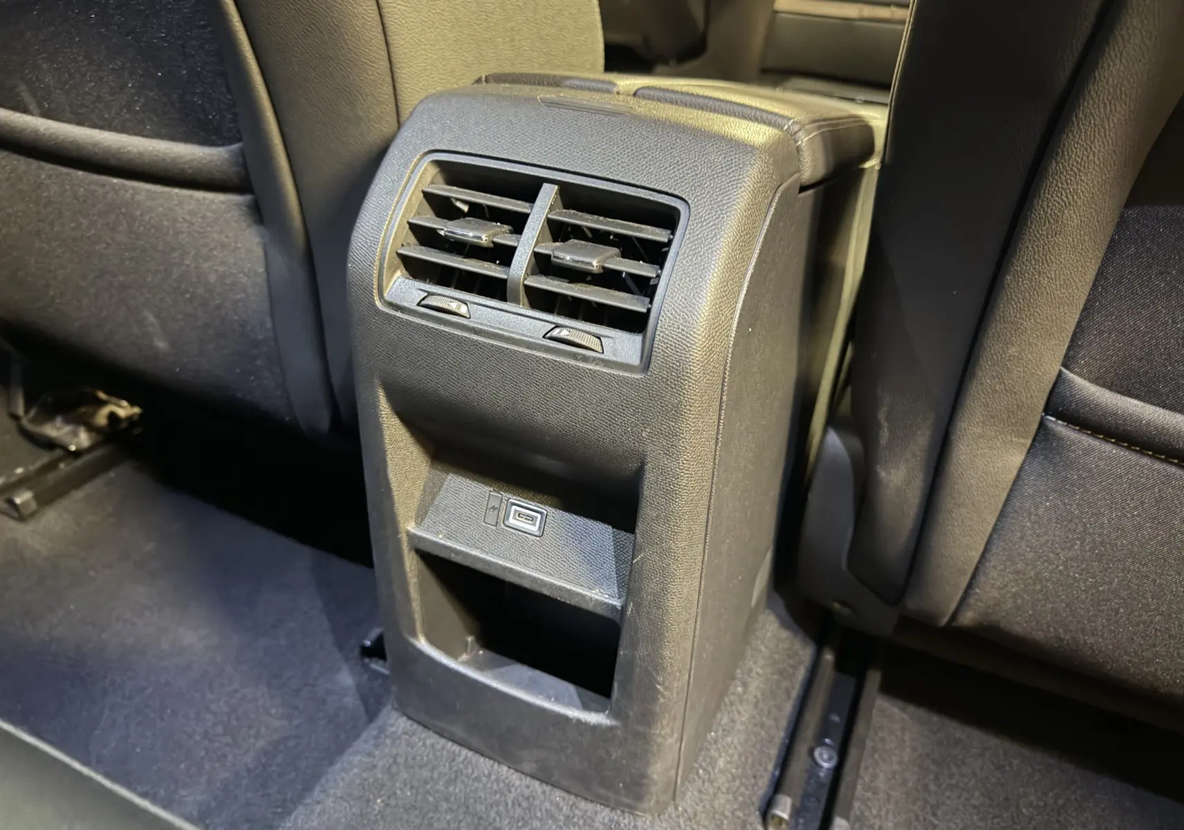 Vue rapprochée de la console arrière noire avec bouches d’aération et port USB dans l’Opel Astra gris 2024.