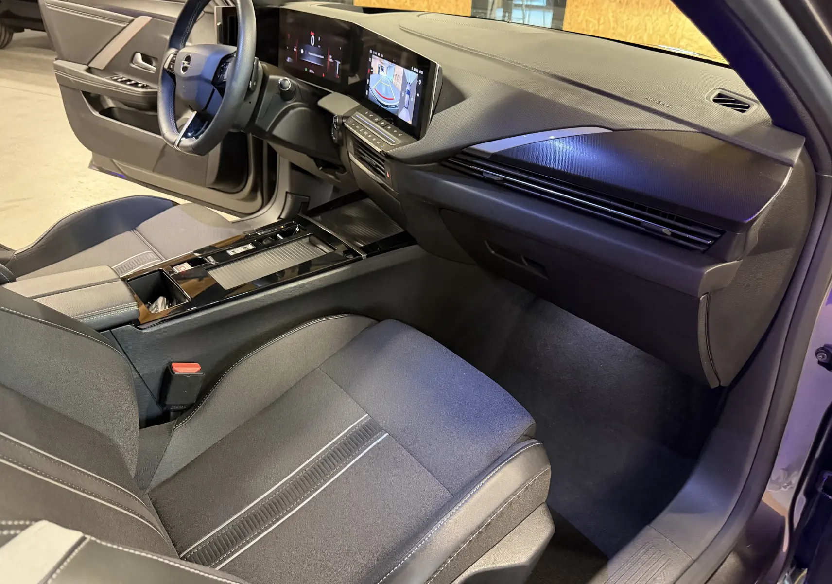Vue intérieure côté passager de l’Opel Astra 2024 gris, avec tableau de bord moderne et écran tactile panoramique.