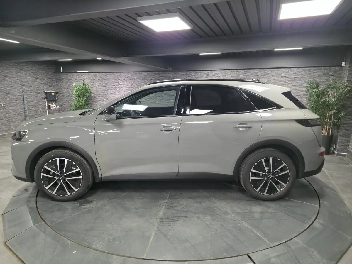 Vue latérale droite du DS7 Crossback gris métallisé 2025 avec jantes alliage noires et toit noir brillant.