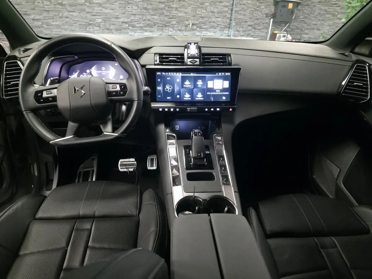 Vue intérieure avant du DS7 Crossback gris, mettant en valeur le volant cuir, l'écran tactile HD et la console centrale moderne.