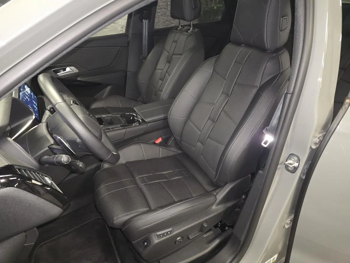 Vue intérieure côté conducteur du DS7 Crossback gris, sièges avant en cuir noir avec surpiqûres et console centrale visible.