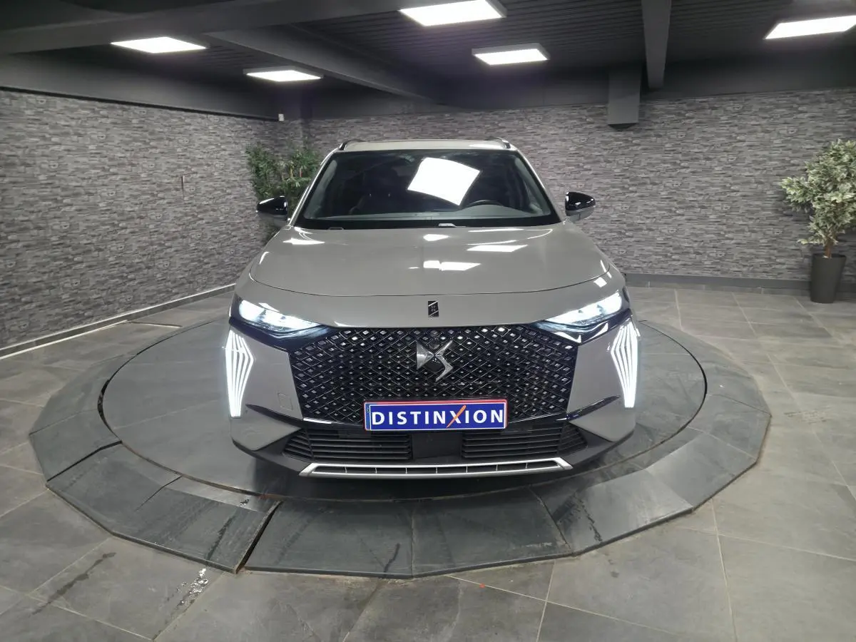 Vue de face du DS7 Crossback gris avec calandre noire à motif diamant et feux LED verticaux allumés.