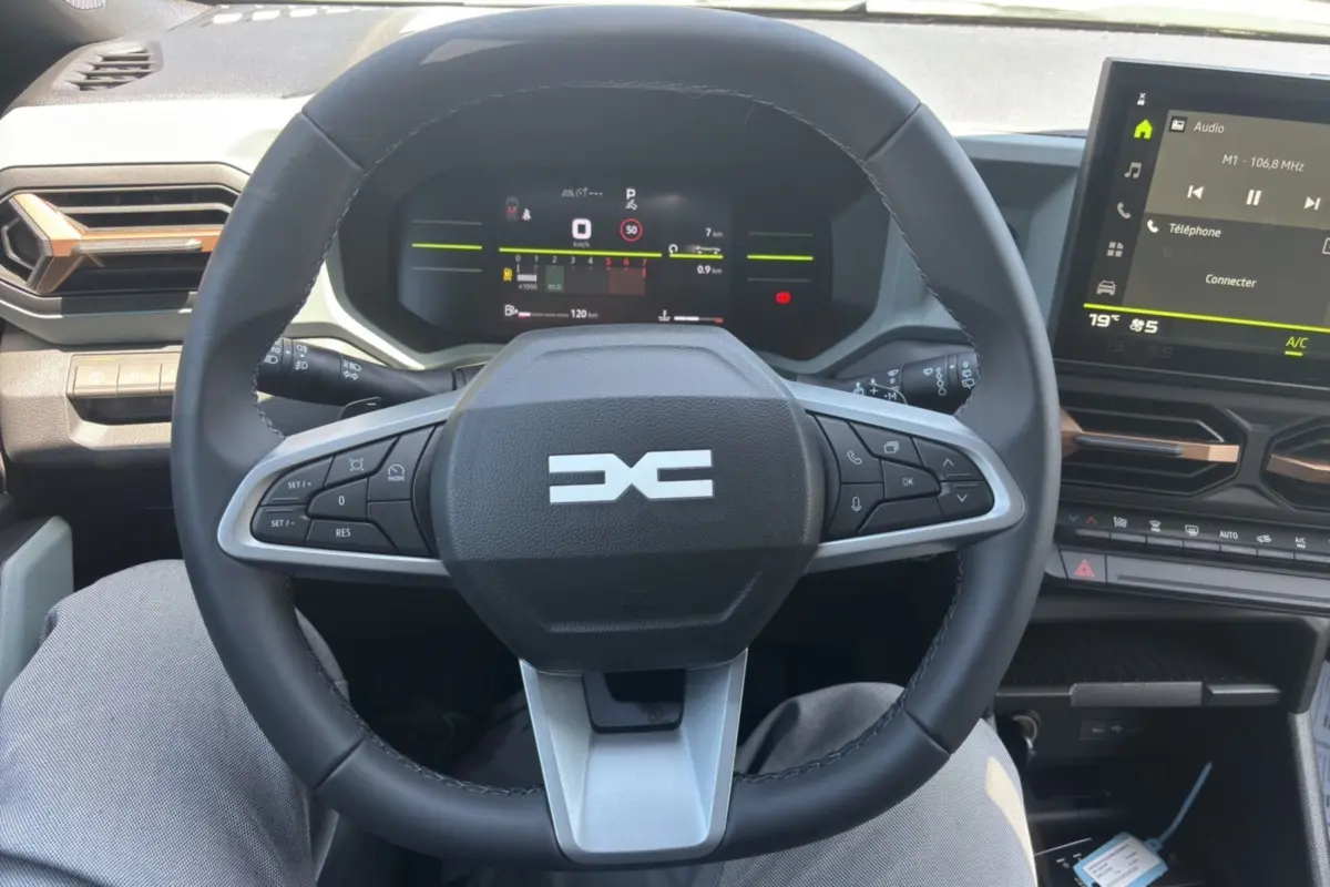 Vue intérieure centrée sur le volant cuir du Dacia Duster 2026 avec tableau de bord digital et écran tactile.