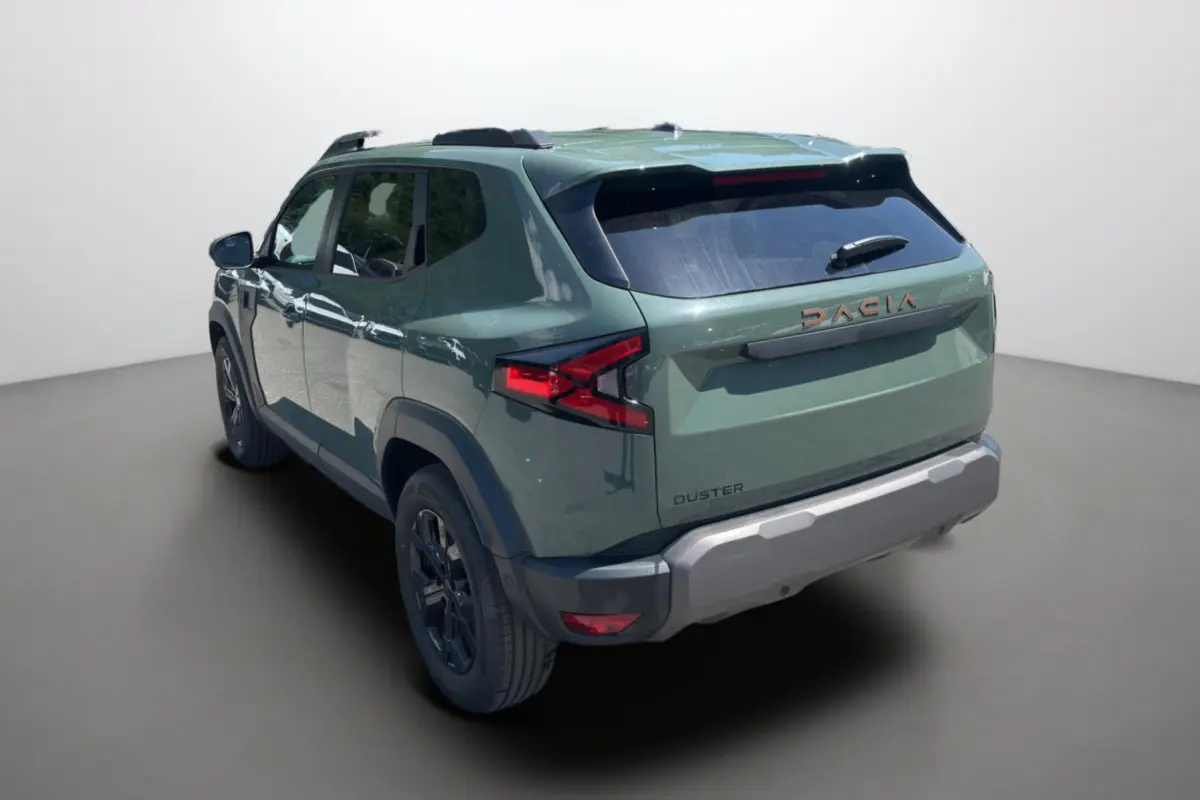 Vue 3/4 arrière droite d’un Dacia Duster 2026 kaki lichen avec barres de toit et jantes alu noires.