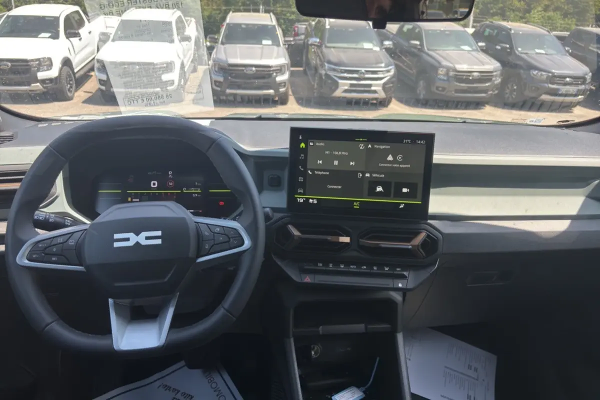 Vue intérieure frontale du tableau de bord du Dacia Duster 2026 kaki avec écran tactile et volant multifonction.