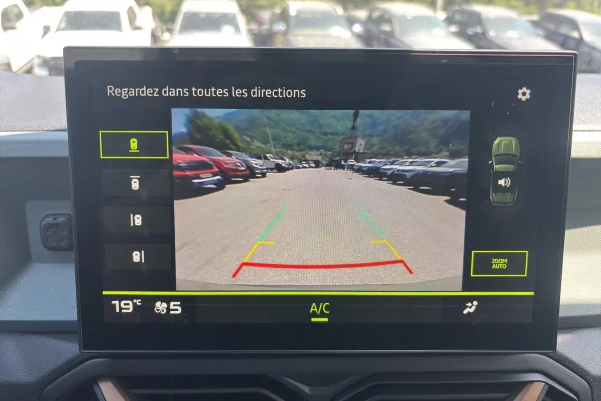 Écran tactile intérieur montrant la caméra de recul du Dacia Duster kaki lichen, vue arrière avec lignes de guidage colorées.