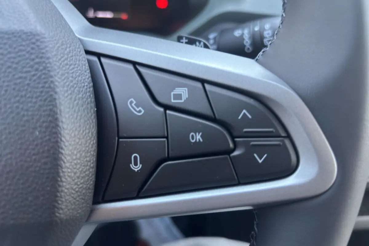 Gros plan sur les commandes multifonctions noires à droite du volant cuir du Dacia Duster 2026.