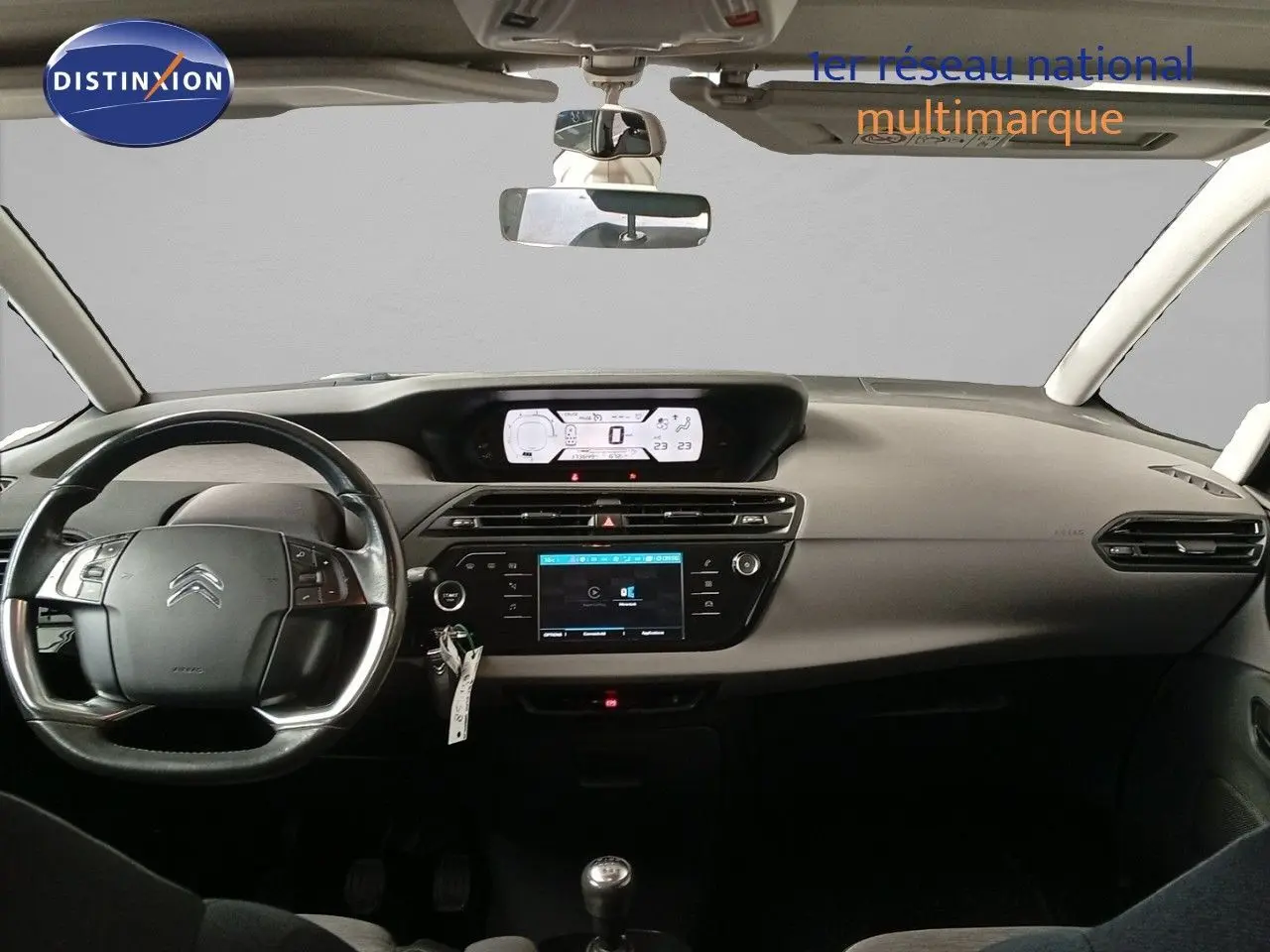 Tableau de bord et volant noir d'une Citroën Grand C4 Picasso blanc, vue frontale intérieure avec écran digital et boîte manuelle.