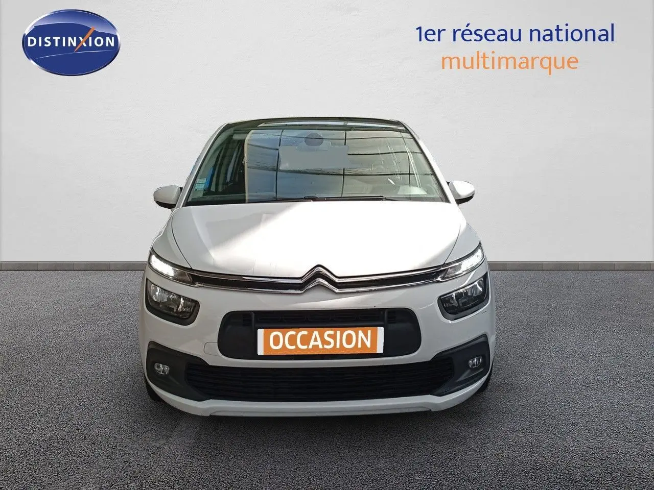 Vue frontale d'une Citroën Grand C4 Picasso blanche de 2016 avec plaque "OCCASION" sur un fond neutre.