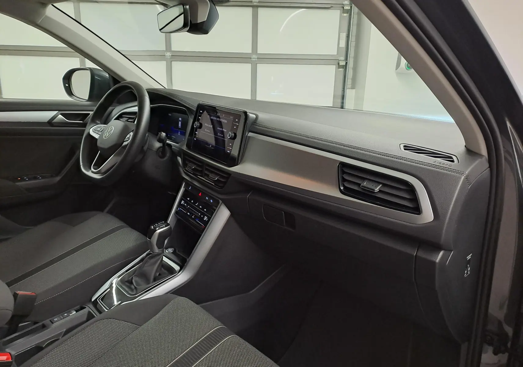 Intérieur avant droit du Volkswagen T-Roc 2024 avec tableau de bord moderne et console centrale épurée.