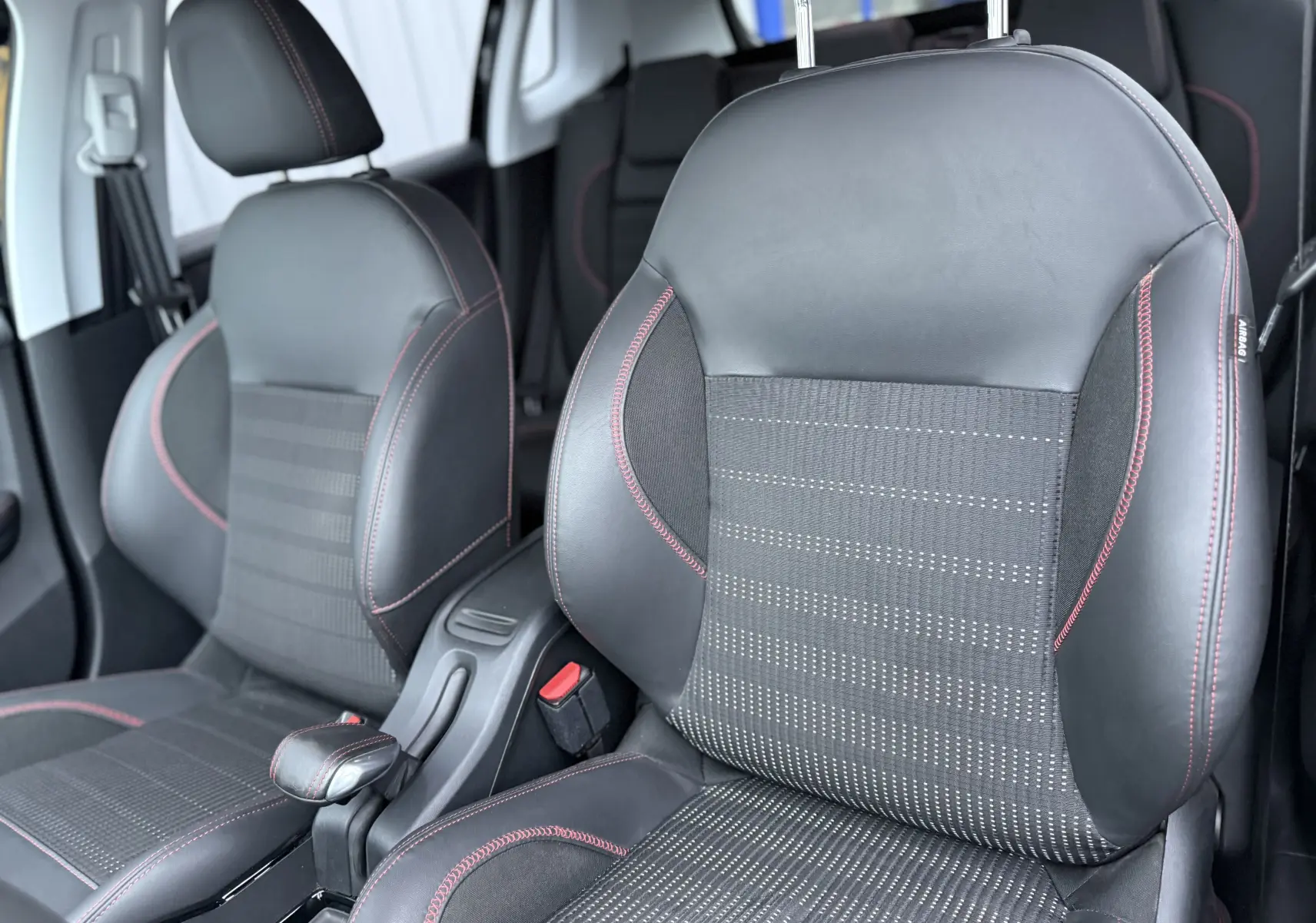 Gros plan sur les sièges avant en cuir noir avec surpiqûres rouges du Peugeot 2008 GT Line 2018, intérieur moderne.