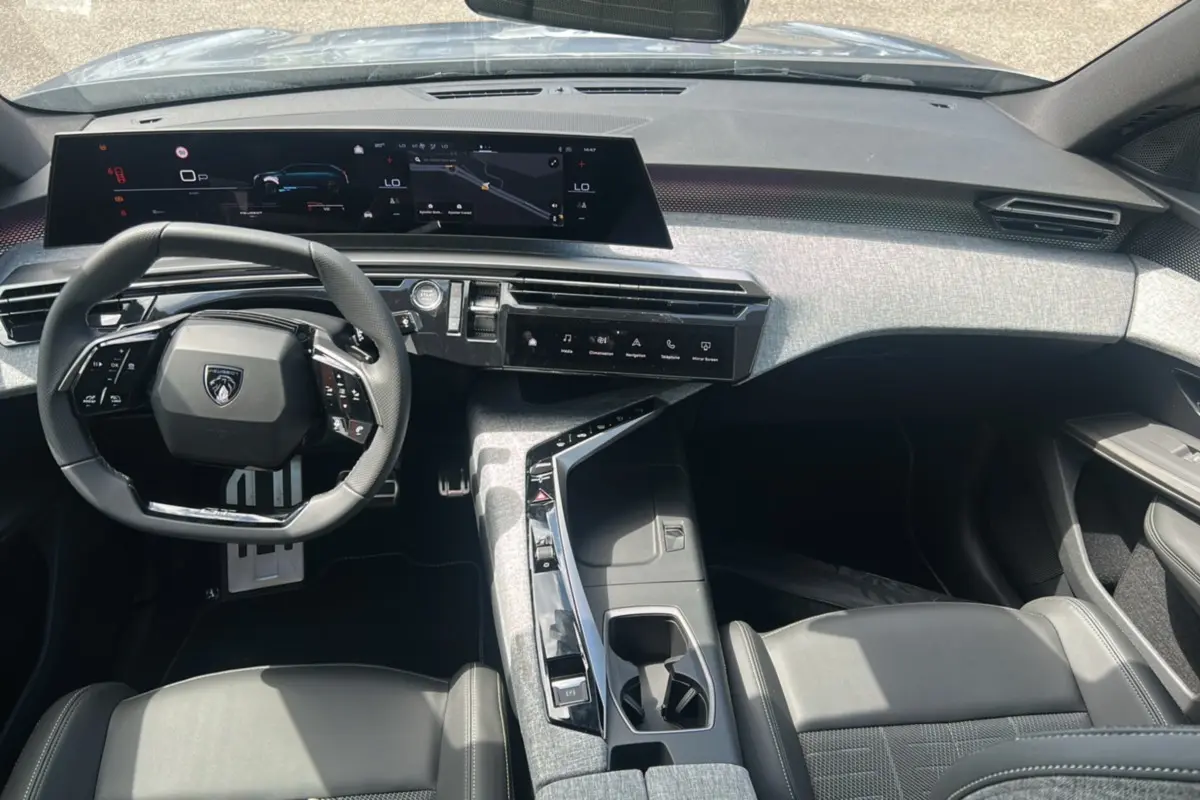 Vue intérieure avant du Peugeot 5008 Hybrid 145 GT 7 places, volant cuir multifonctions et tableau de bord numérique large.