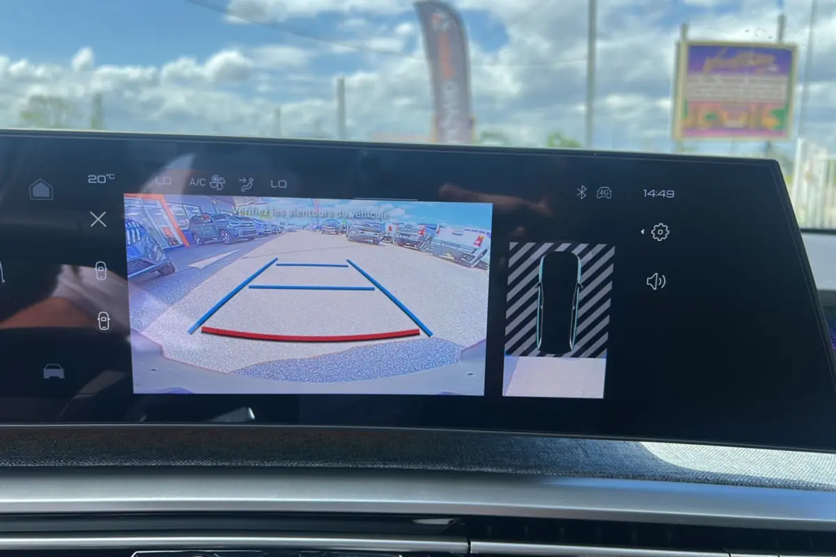 Écran tactile intérieur montrant la caméra de recul et l’aide au stationnement du Peugeot 5008 gris Artense hybride 2025.