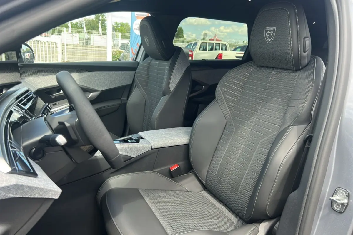 Vue intérieure côté conducteur du Peugeot 5008 Hybrid 145 GT 7 places, sièges tissu et cuir gris avec logo Peugeot brodé.