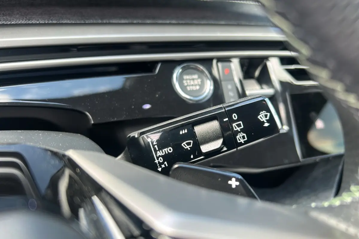 Gros plan sur la commande d’essuie-glace et le bouton start/stop du tableau de bord d’un Peugeot 5008 gris artense 2025.