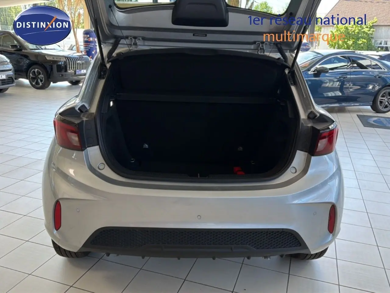Vue arrière d'une MG3 Cosmic Silver Metal 2026 avec coffre ouvert, en intérieur de showroom lumineux.