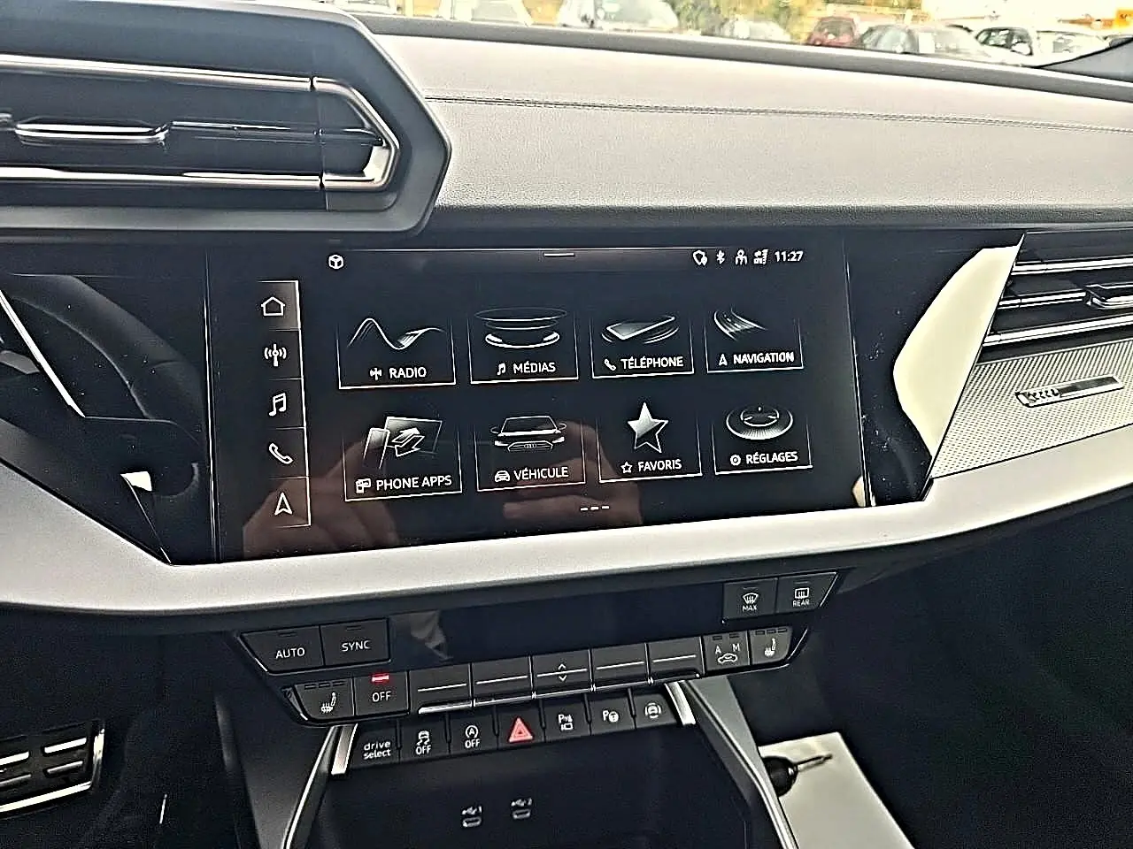 Tableau de bord de l'Audi A3 Sportback 2026 avec écran tactile multifonction et commandes climatisation, vue de face intérieure.
