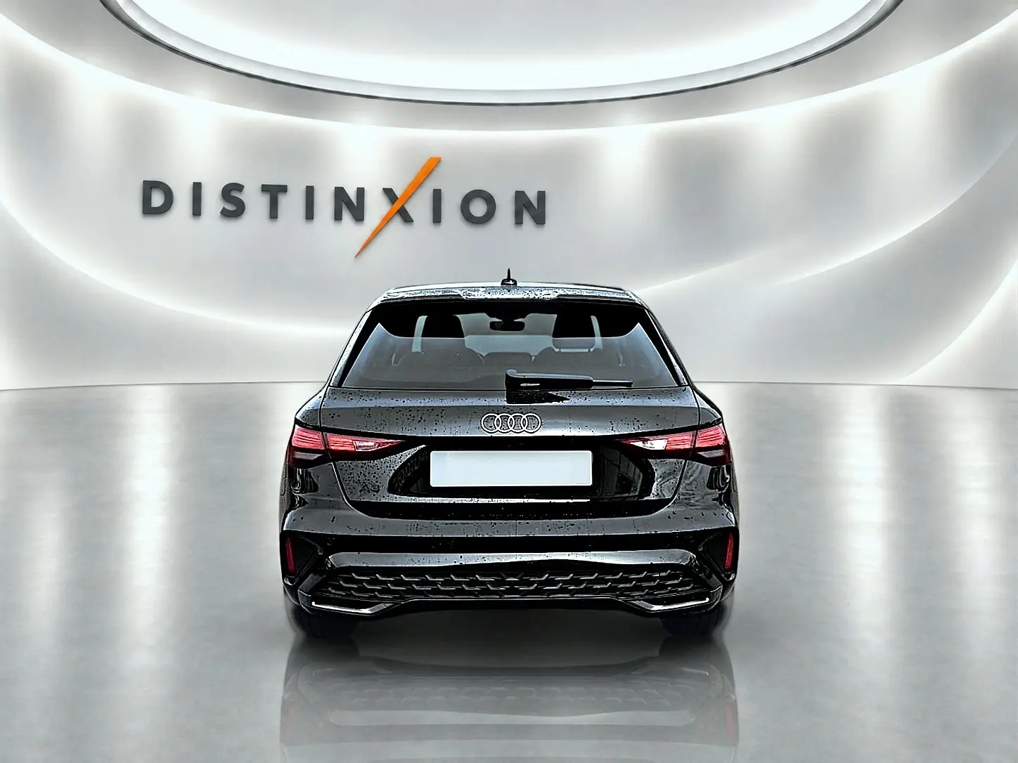 Vue arrière d'une Audi A3 Sportback 1.5 TFSI noire Mythos avec feux LED et becquet arrière dans un studio lumineux.