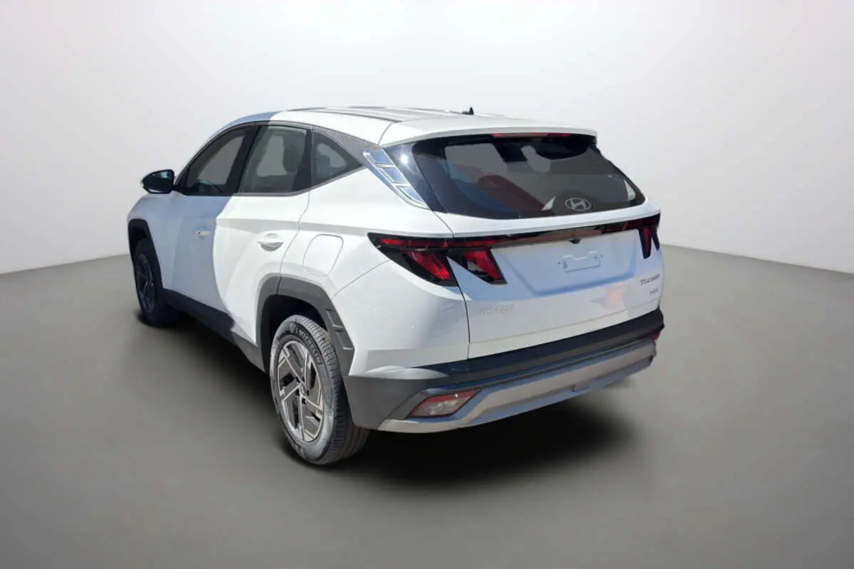 Vue 3/4 arrière gauche du Hyundai Tucson blanc atlas 2026 avec feux arrière LED et jantes alu 17 pouces.