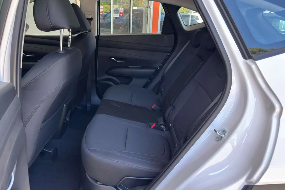 Vue intérieure côté gauche sur la banquette arrière tissu noire du Hyundai Tucson blanc atlas 2026 avec porte ouverte.