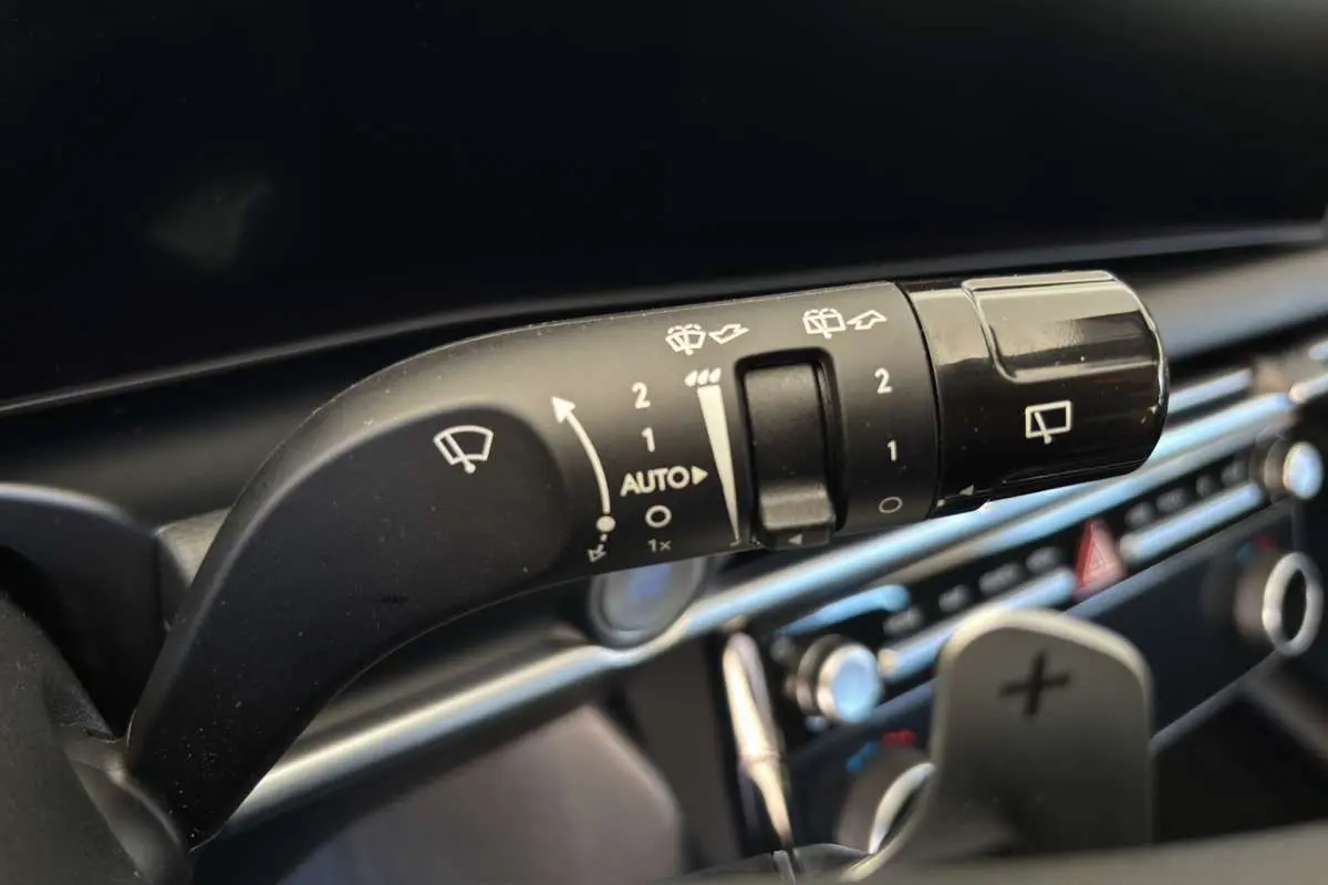 Gros plan sur la commande d’essuie-glace du Hyundai Tucson 1.6 T-GDI HEV 239 blanc atlas, intérieur moderne avec palettes au volant.