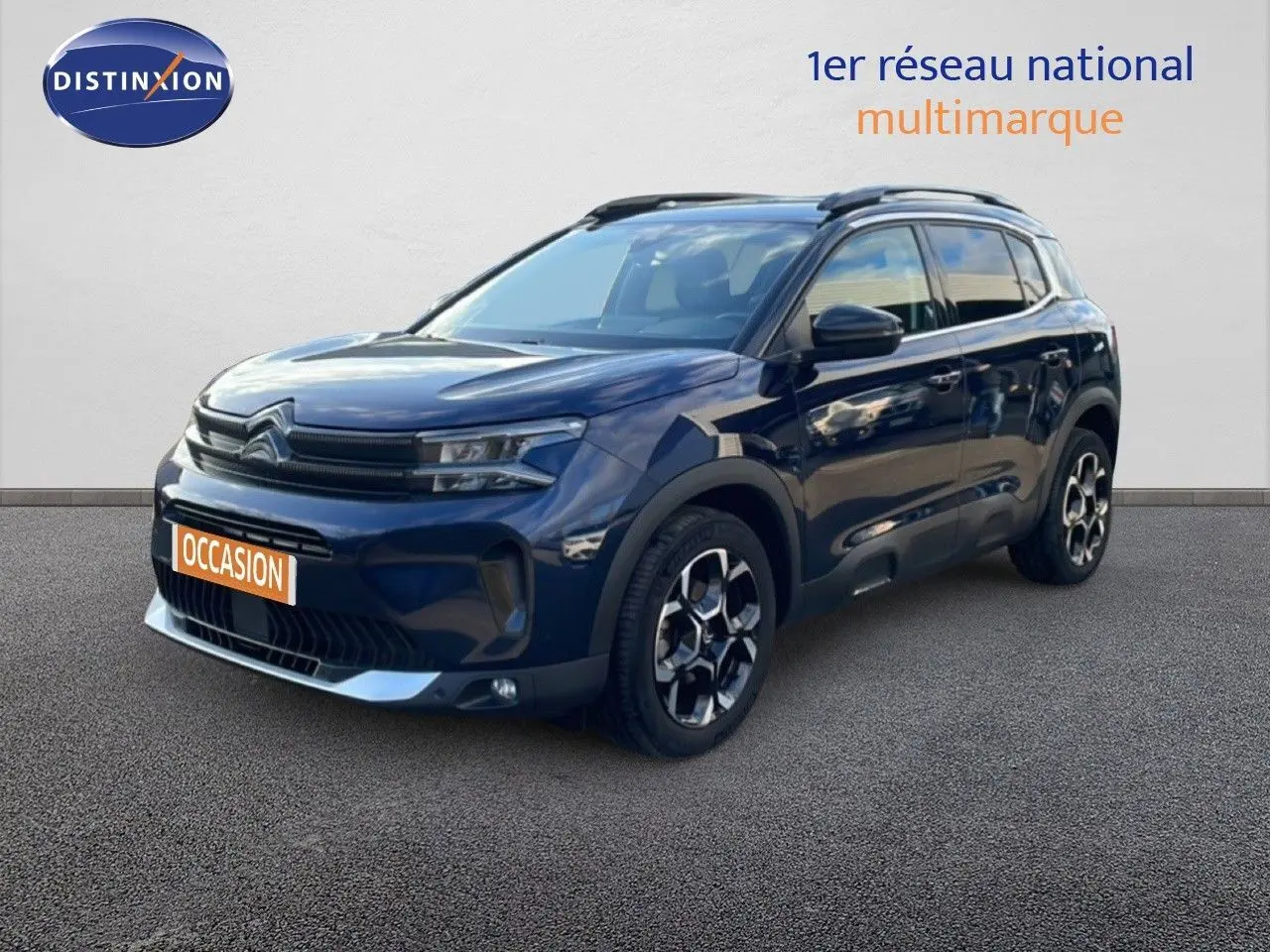 Vue 3/4 avant d'un Citroën C5 Aircross bleu Eclipse Métal avec jantes bi-ton et barres de toit noires.