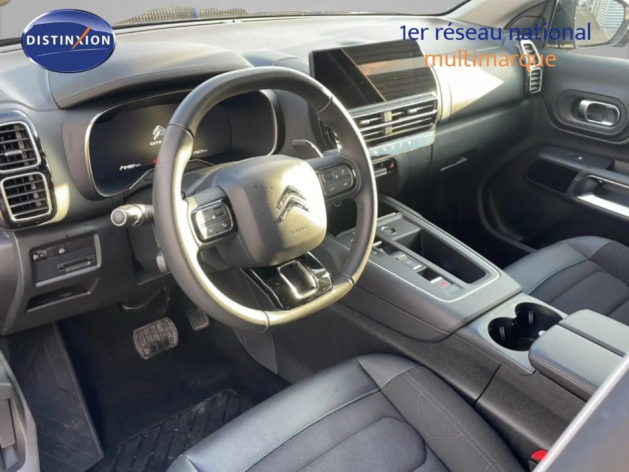 Vue intérieure de la Citroën C5 Aircross 2023, côté conducteur, avec volant multifonction et sellerie noire.