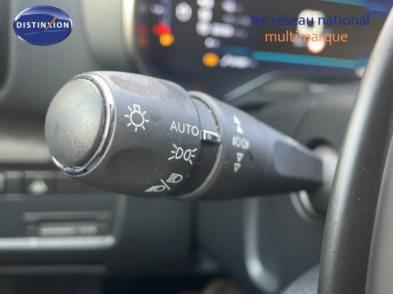 Gros plan sur la commande des feux automatique dans l'habitacle d'une Citroën C5 Aircross 2023 bleu Eclipse Metal.