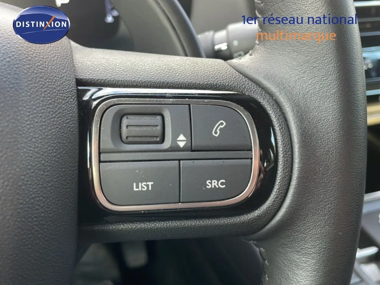 Gros plan sur les commandes noires du volant du Citroën C5 Aircross 2023 bleu Eclipse Metal, avec boutons d’appel et liste.