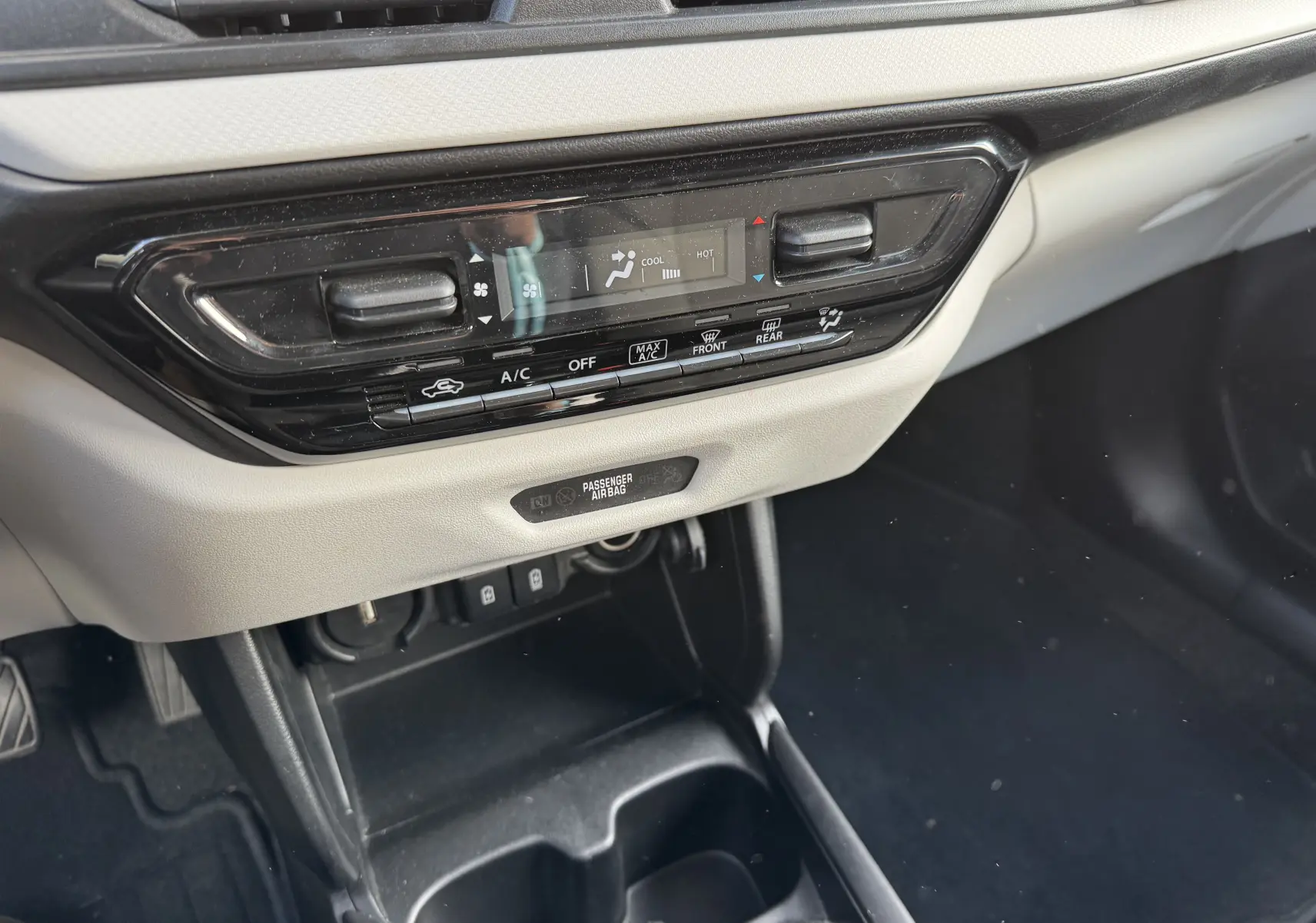 Détail du tableau de bord beige et noir de la Suzuki Swift 1.2 Hybrid Privilege MY24 avec commandes climatisation digitale.