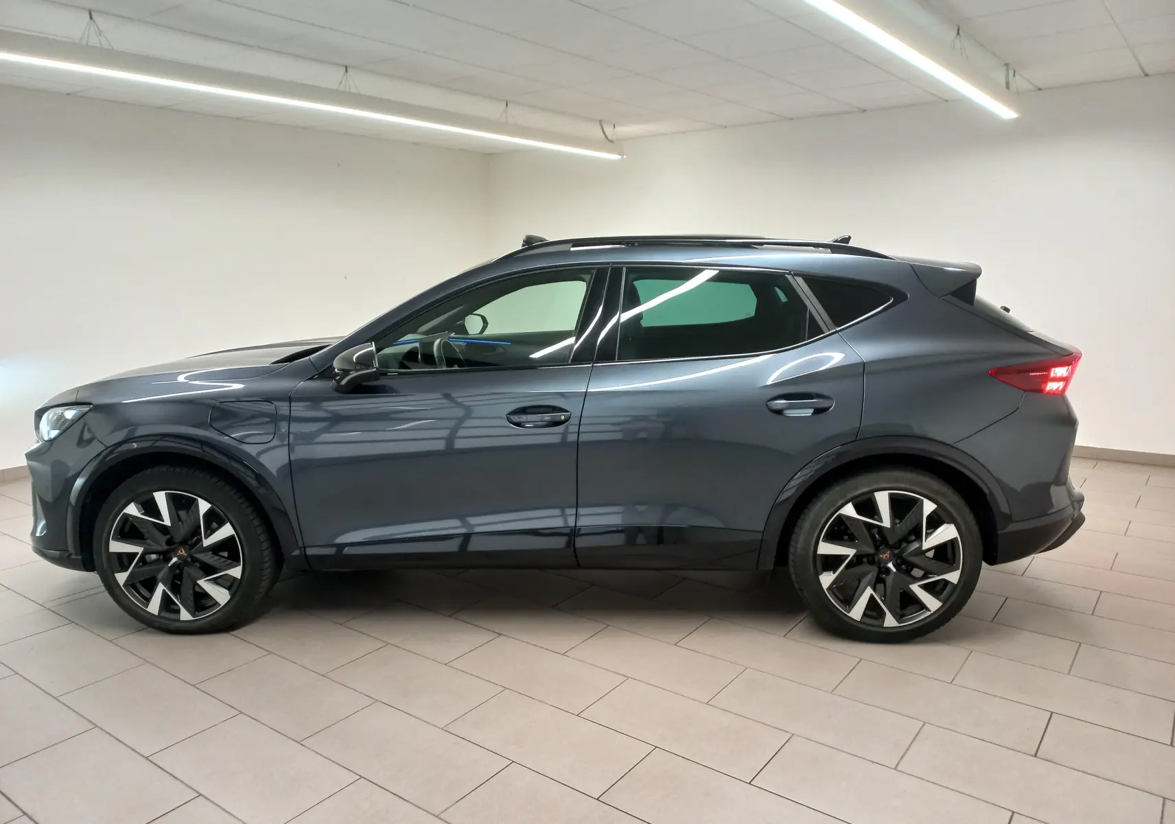 Vue de profil côté gauche du CUPRA Formentor gris magnétique 2025 avec toit ouvrant panoramique et jantes distinctives.
