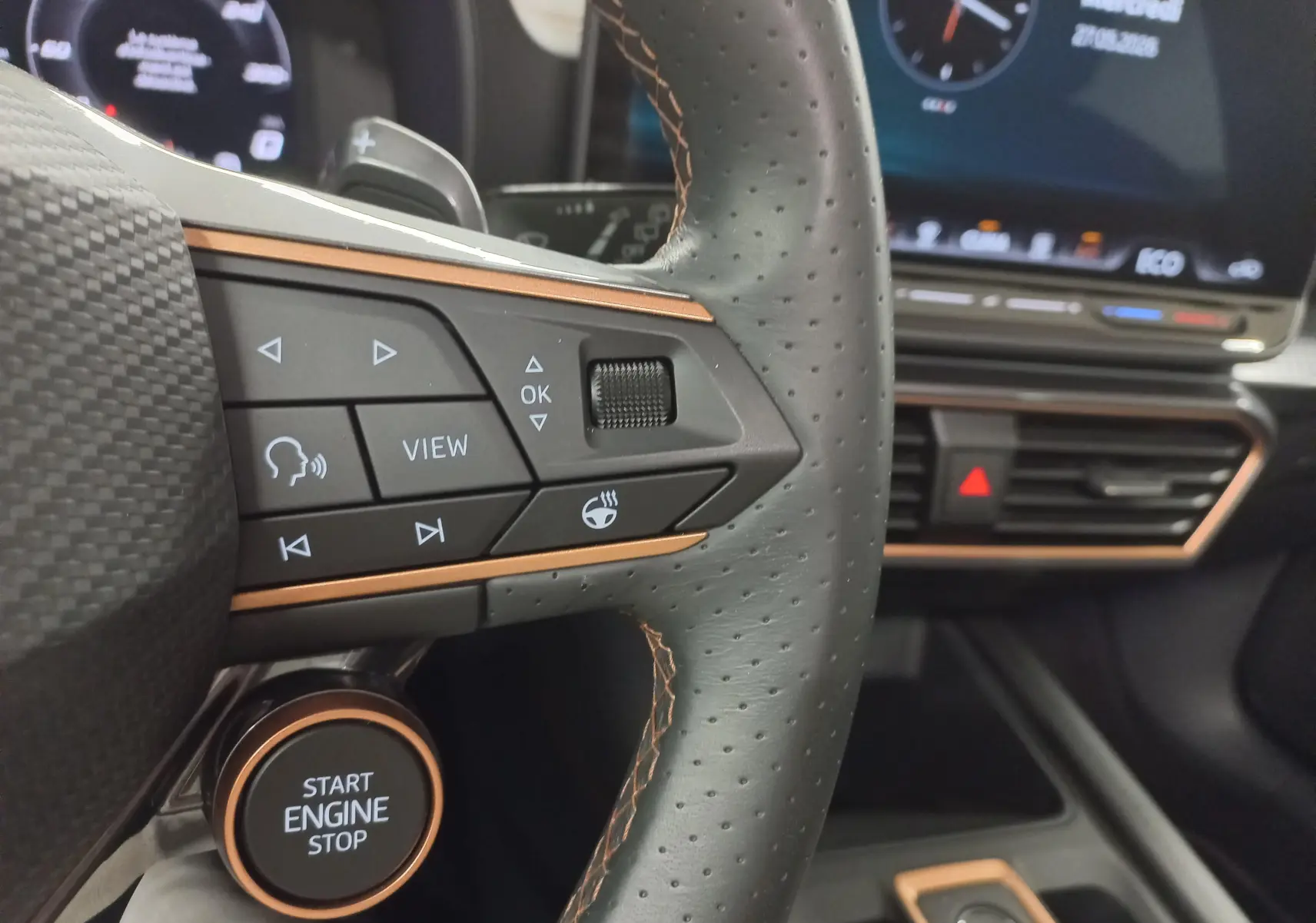 Gros plan sur le volant perforé et les commandes du CUPRA Formentor 1.5 EHybrid 2025 avec surpiqûres cuivre et bouton start/stop.