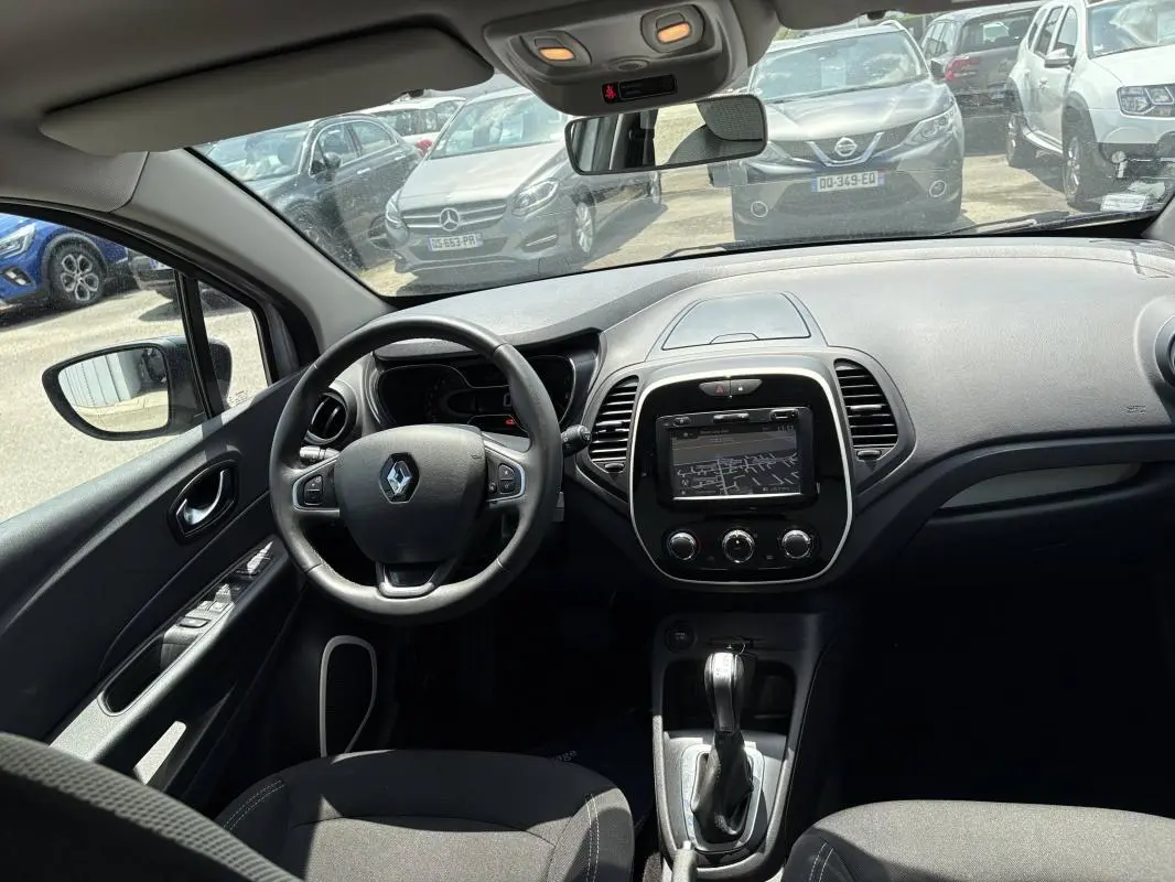 Vue intérieure avant du Renault Captur gris 2017, montrant le volant multifonction et l’écran tactile central.