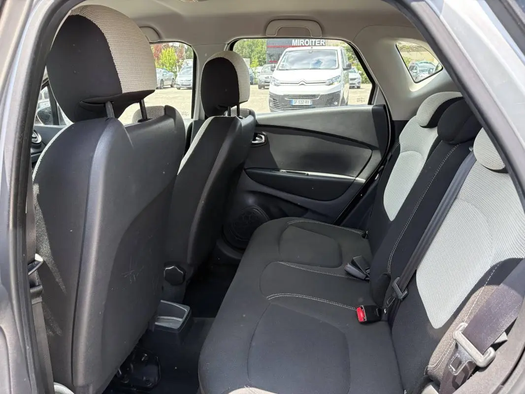 Vue intérieure arrière côté gauche du Renault Captur gris, montrant les sièges arrière en tissu bicolore noir et gris.