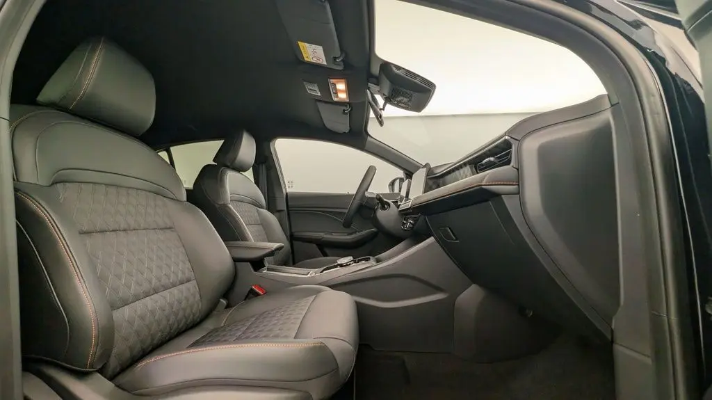 Vue intérieure côté passager du MG3 1.5L Hybrid+ 195CH Luxury avec sièges noirs en cuir et surpiqûres orange.