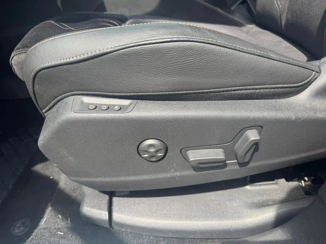 Détail du côté gauche du siège avant en cuir noir avec commandes électriques sur DS7 Hybride Rechargeable 2024.
