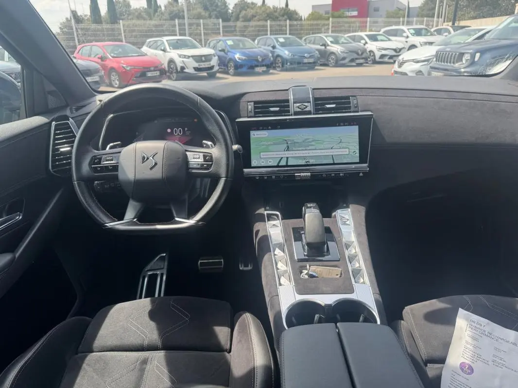 Vue intérieure avant du DS7 2024 hybride rechargeable, mettant en valeur le volant DS, l'écran tactile large et la console centrale en alcantara.