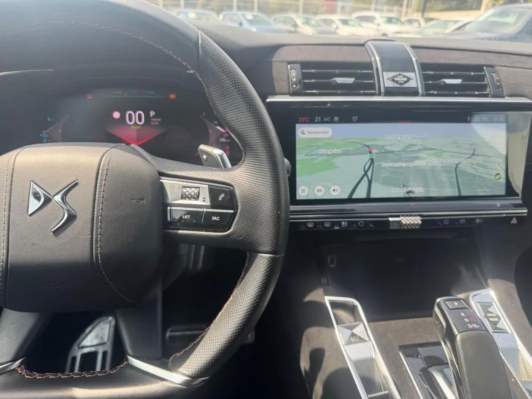 Vue intérieure centrée sur le volant DS et l'écran tactile du tableau de bord du DS7 hybride gris foncé 2024.