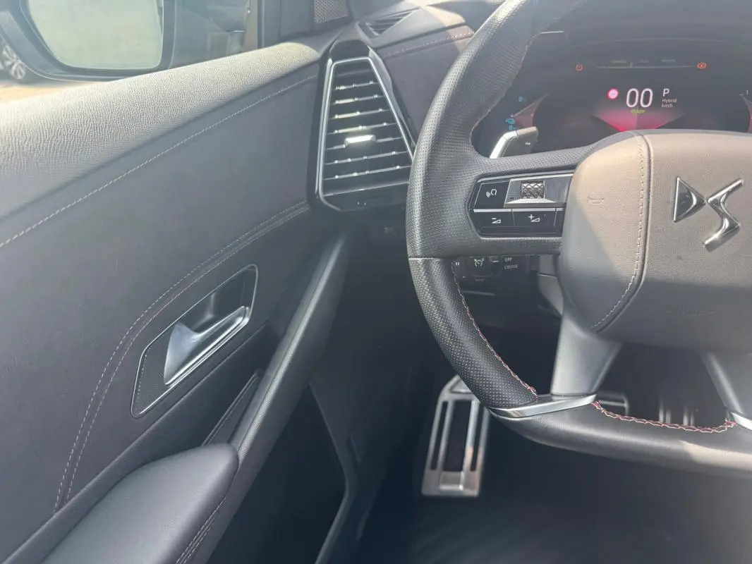 Vue intérieure côté gauche du volant du DS7 gris foncé, avec volant multifonction et tableau de bord numérique.