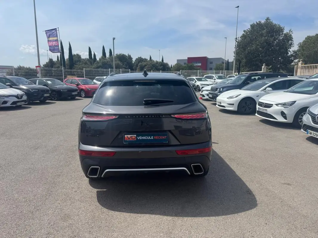 Vue arrière d'un DS7 gris foncé 2024 avec feux LED étirés, double sortie d'échappement et barres de toit visibles.