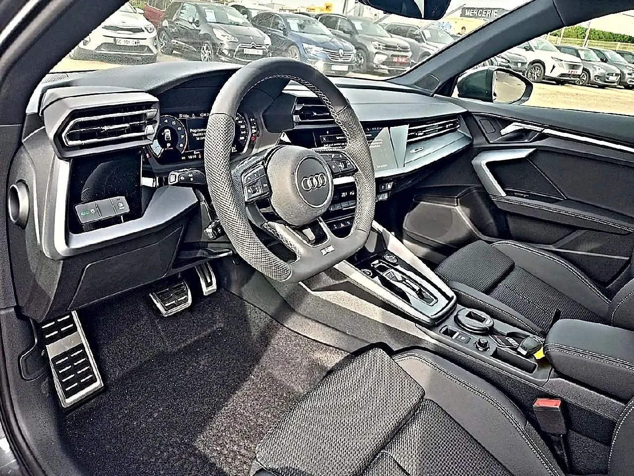 Vue intérieure côté conducteur de l'Audi A3 Sportback 2026, avec volant sport cuir et console centrale moderne noire.