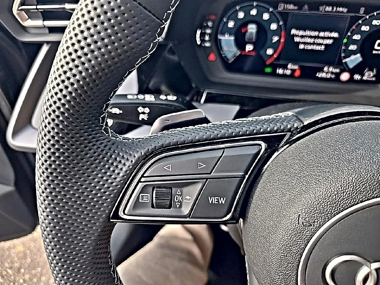 Gros plan sur le volant cuir perforé de l'Audi A3 Sportback 2026 avec commandes multifonctions et tableau de bord digital.