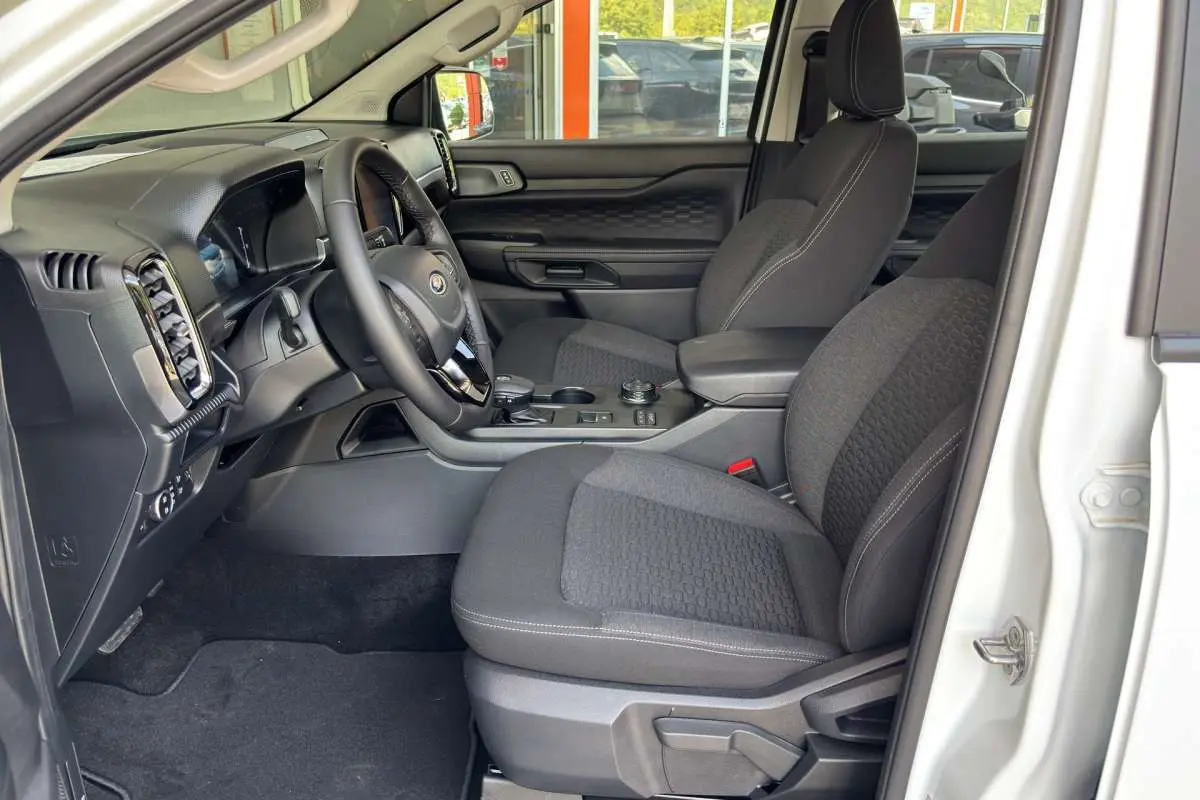 Vue intérieure côté conducteur du Ford Ranger blanc glacier 2026, avec sièges tissu et tableau de bord moderne.